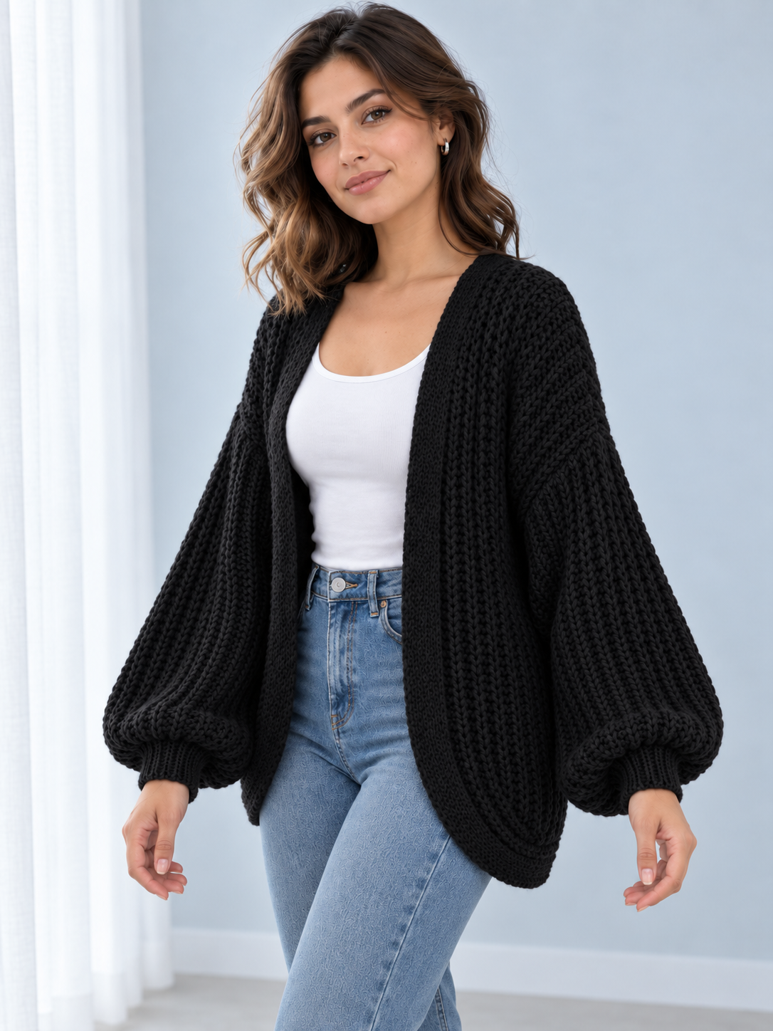 Female model wearing black open-front lantern-sleeve cardigan, angle view